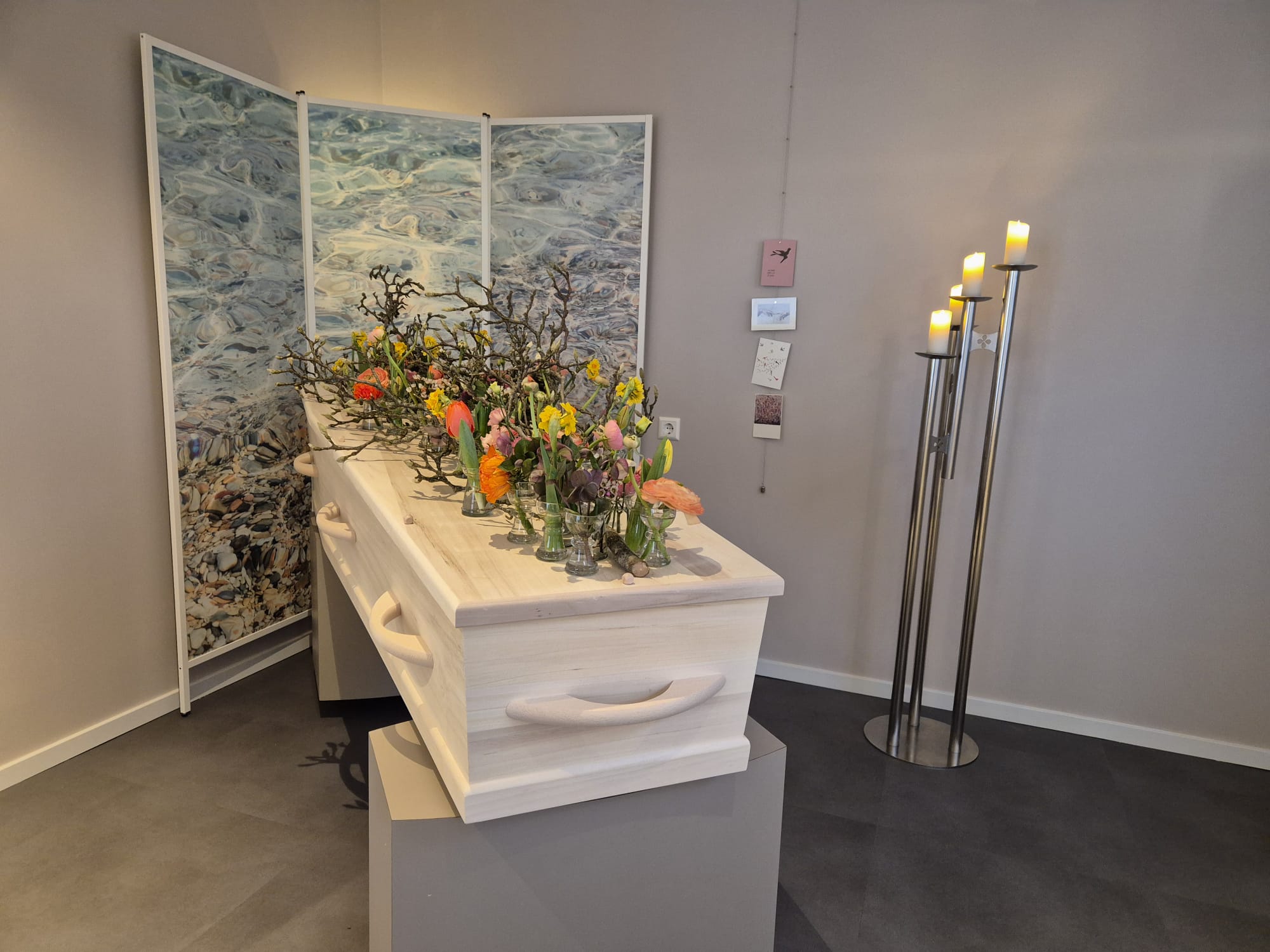 Een opbaring met bloemen in een rustige afscheidsruimte